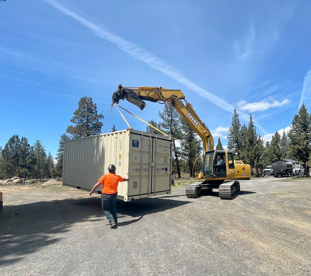Cascade Vaults - 20' storage container being moved by an excavator.